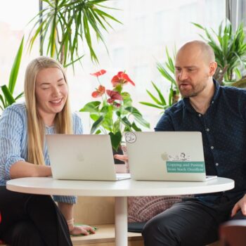 kaksi ihmistä kannettavien tietokoneiden ääressä